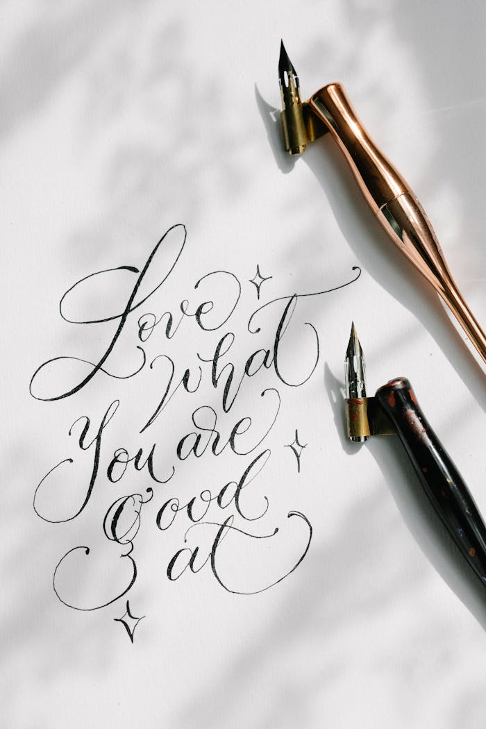 Handwritten calligraphy quote on white paper with decorative pens, featuring a motivational message.